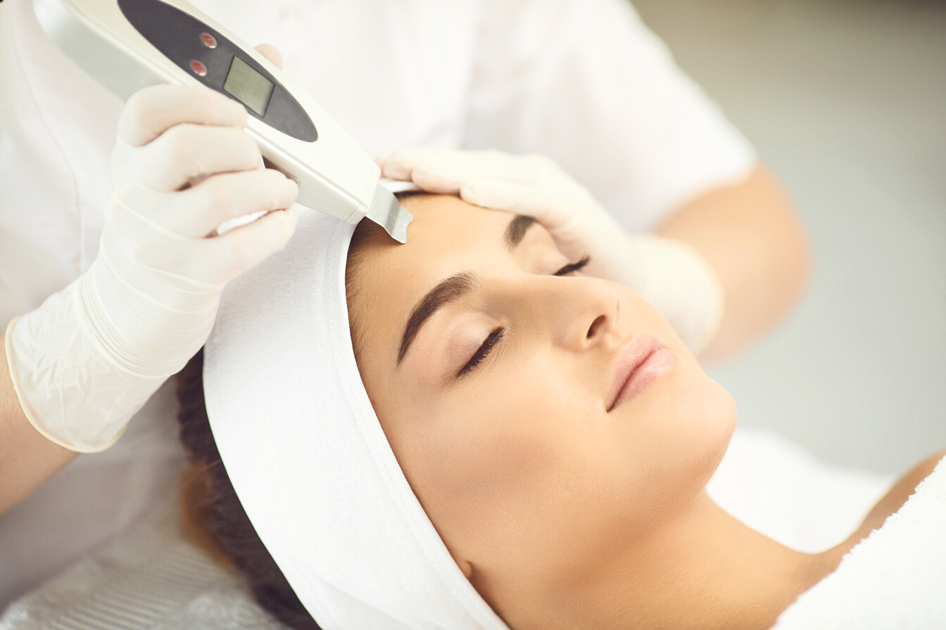 Relaxed Woman Getting Ultrasound Apparatus Facial Cleaning from Cosmetologist